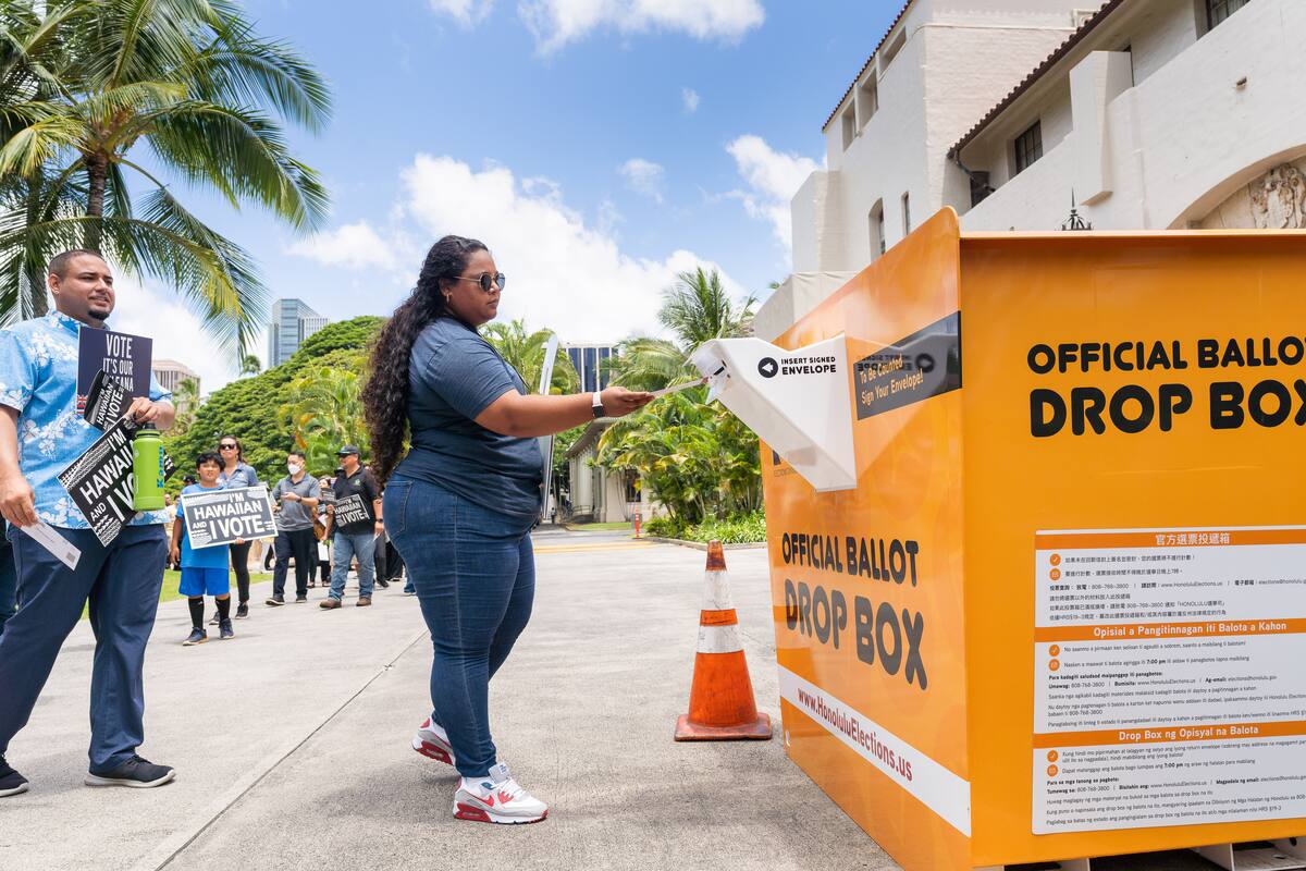 Community member placing a ballot in the drop box